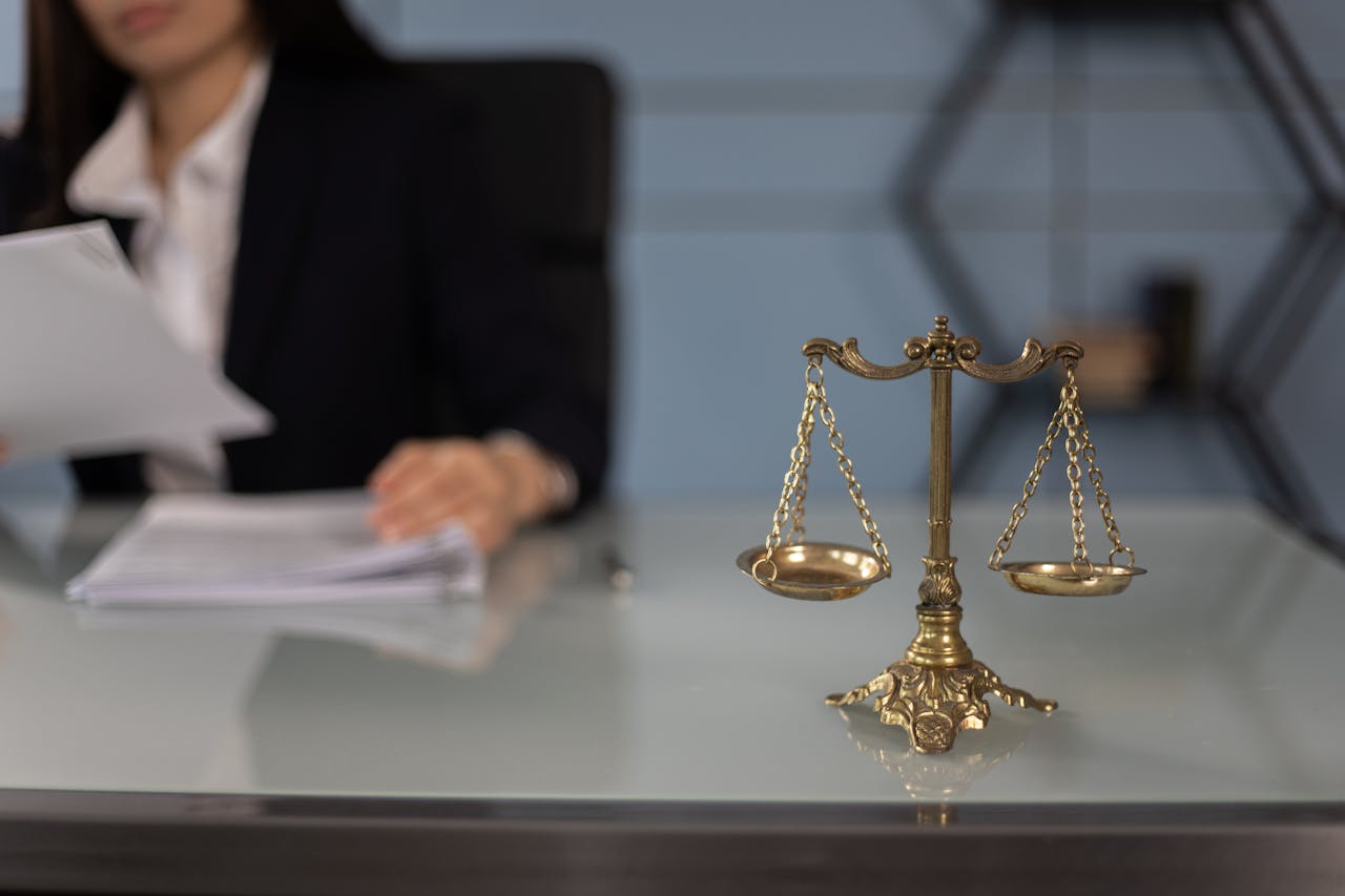 legal-scales-in-foreground-person-looking-at-papers-in-background legal-scales-in-foreground-person-looking-at-papers-in-background